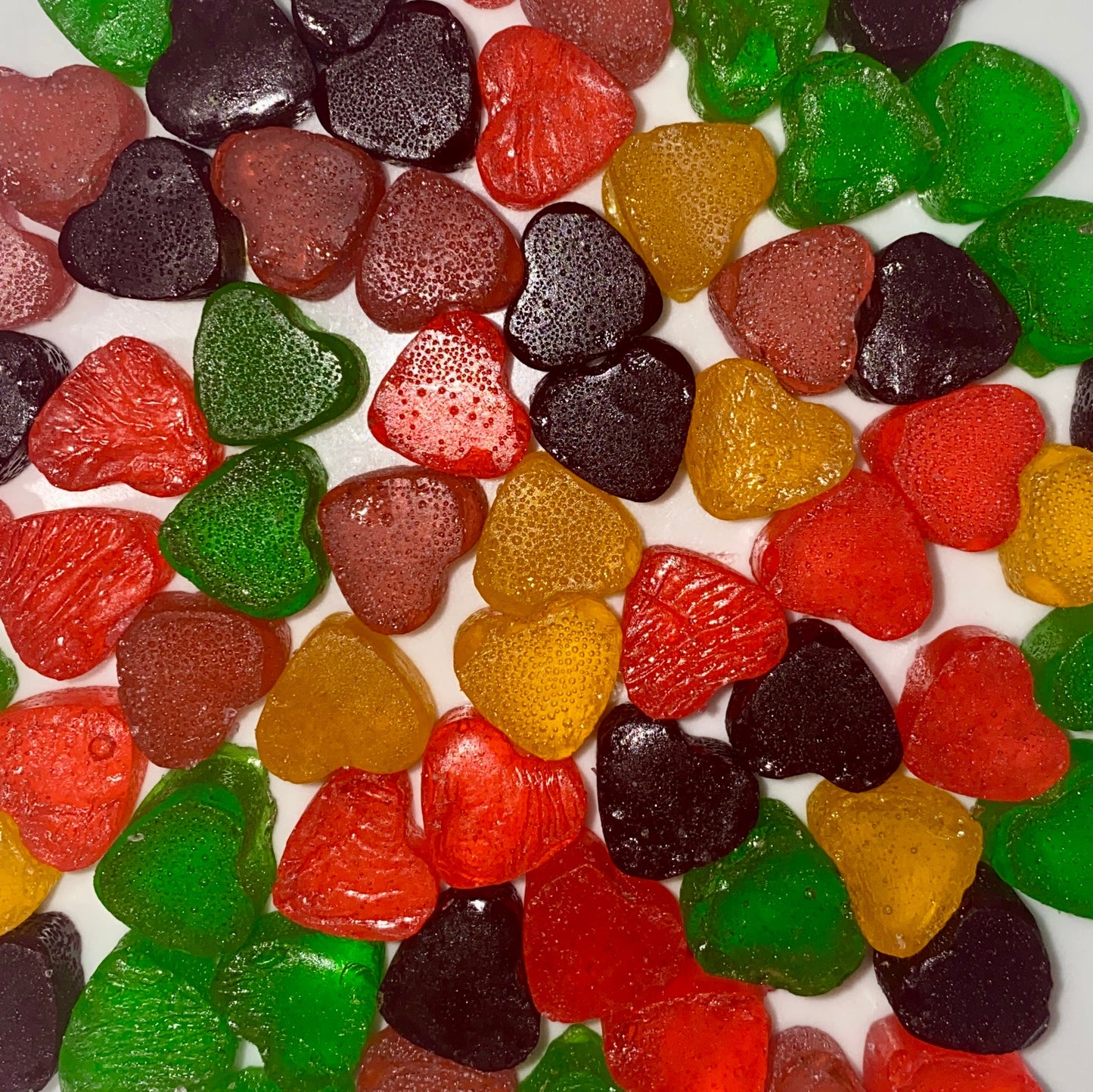 Assorted fruit flavored candy hearts on a white background